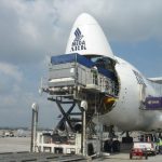 Large cargo boxes being loaded on the back a airliners.