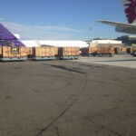 Wooden crates getting loaded into air planes at an airport.